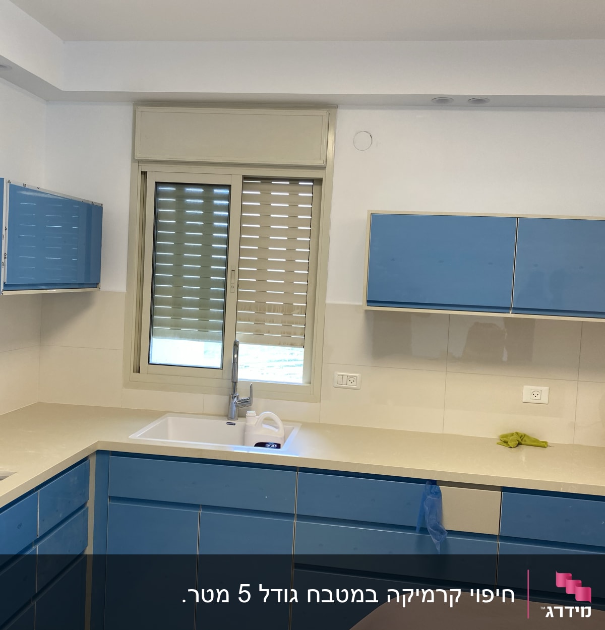 מטבח עם ארונות כחולים, כיור וברז מותקנים